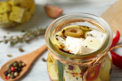 Photo of Jar with feta cheese marinated in oil on table, closeup. Pickled food