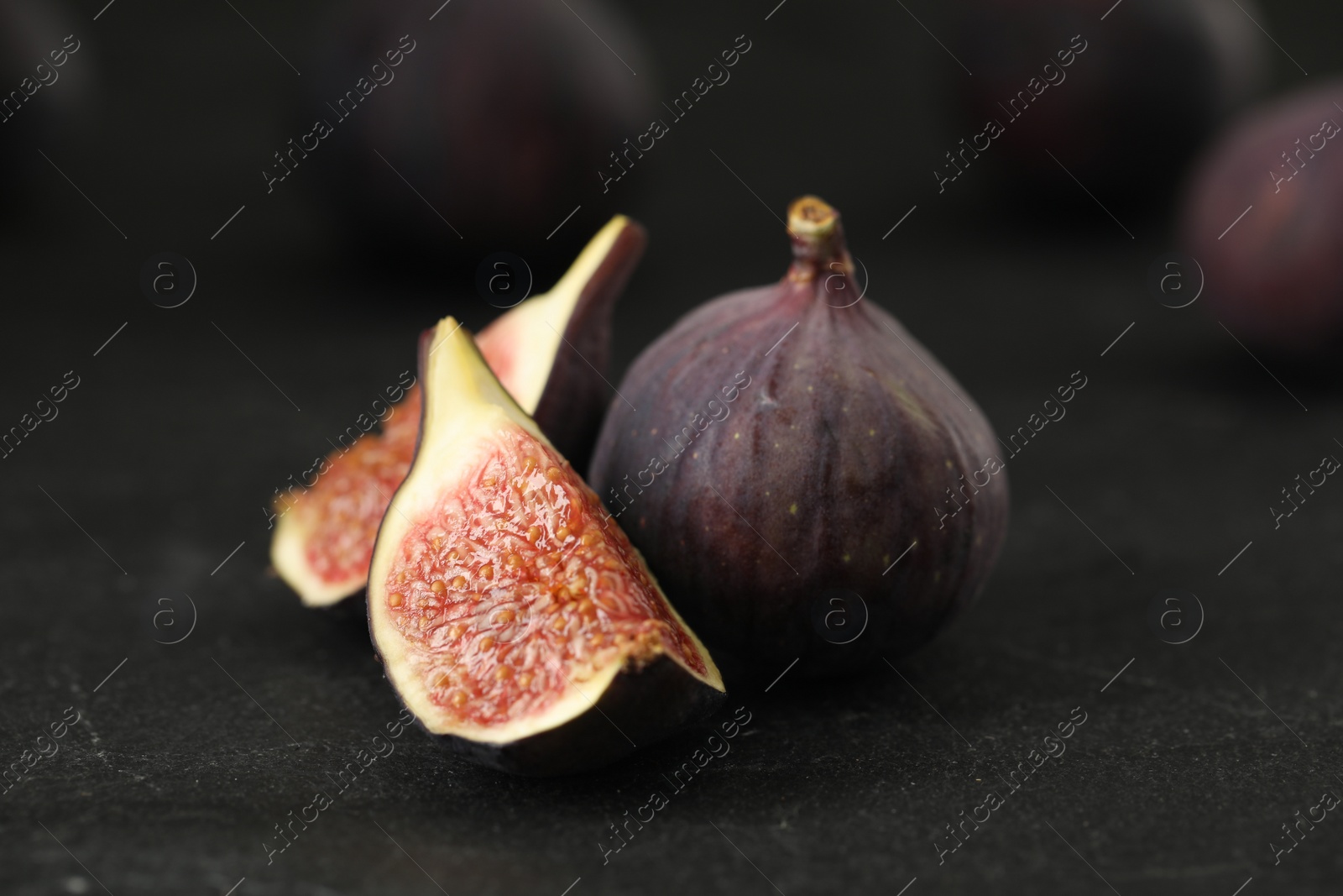 Photo of Tasty raw figs on black slate table, closeup