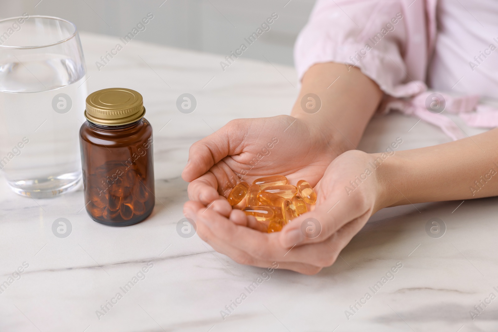 Photo of Woman with vitamin pills at table indoors, closeup