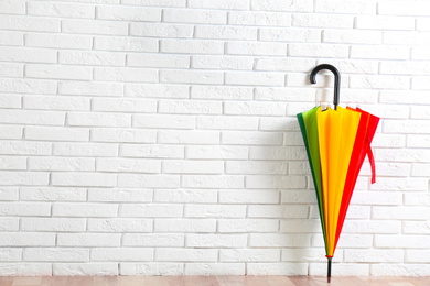 Photo of Beautiful colorful umbrella near white brick wall. Space for text