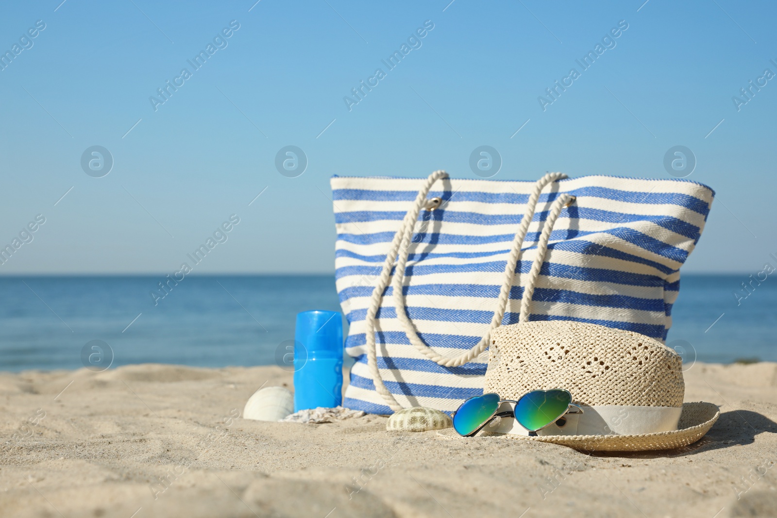 Photo of Stylish beach accessories on sandy sea shore