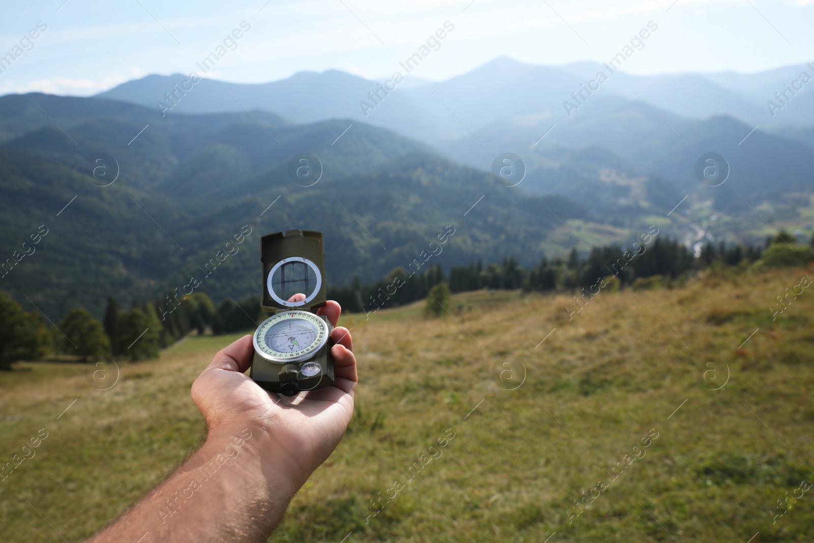 Photo of Man using compass during journey in mountains, closeup