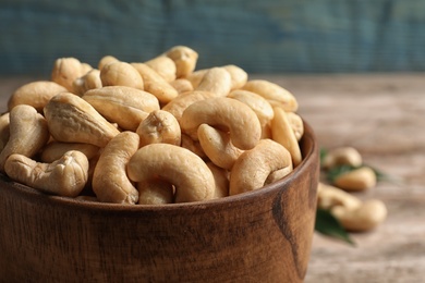 Photo of Tasty cashew nuts in wooden bowl on table, closeup