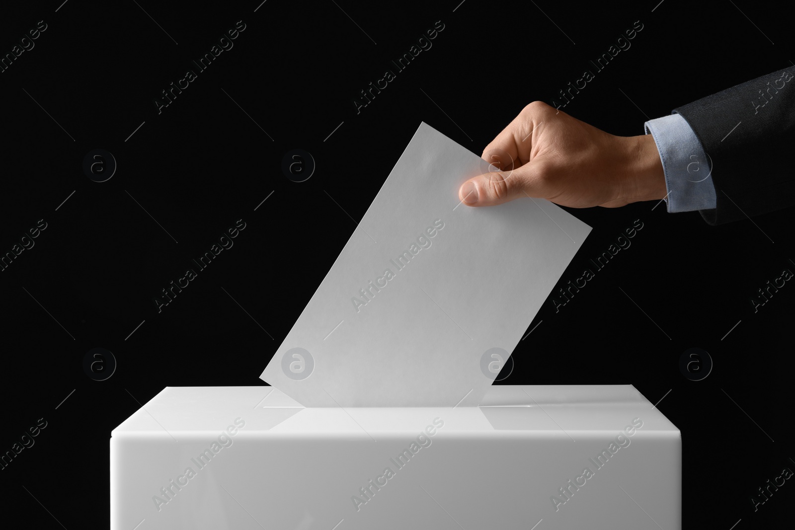 Photo of Man putting his vote into ballot box on black background, closeup