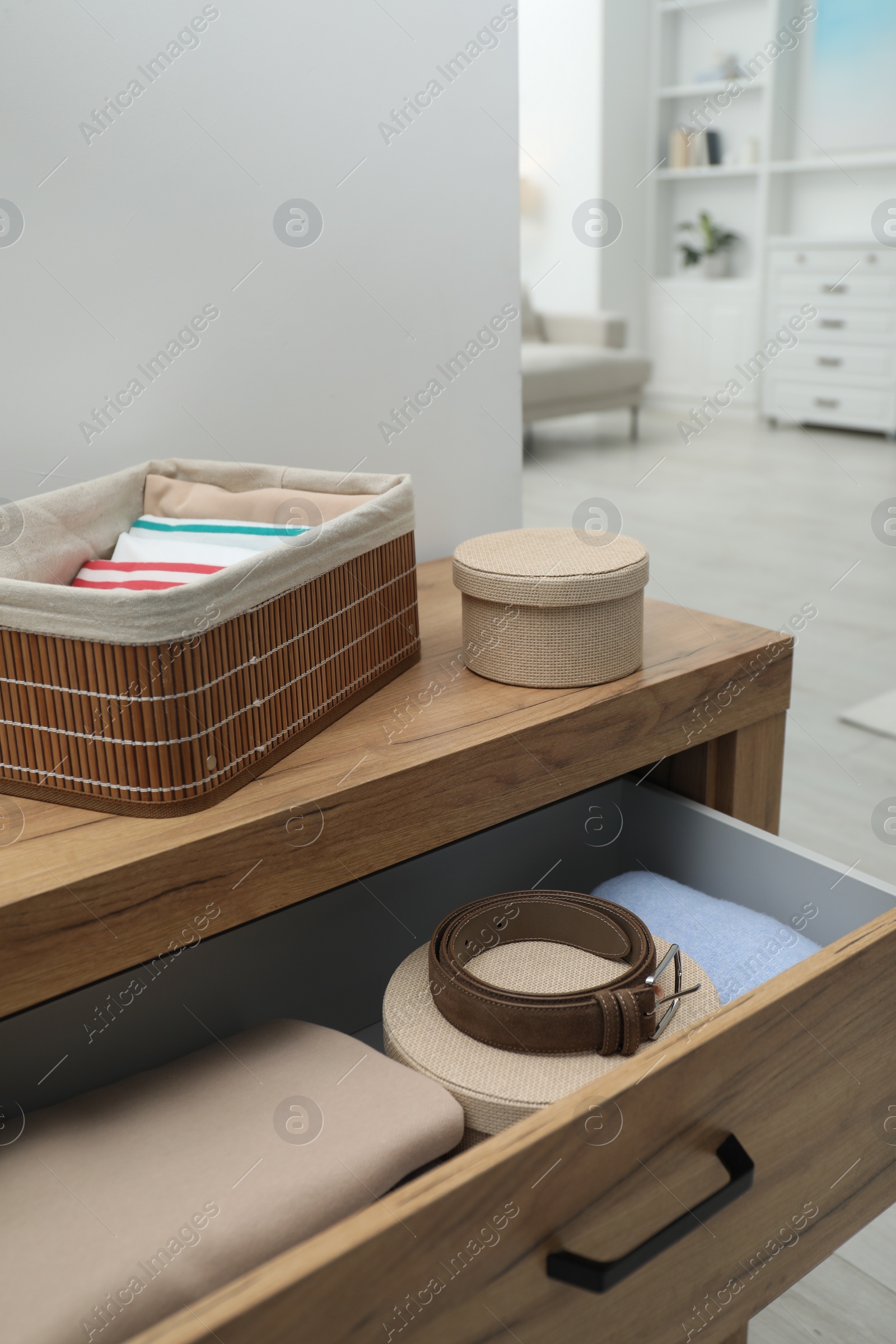 Photo of Chest of drawers with different folded clothes and accessories indoors, closeup