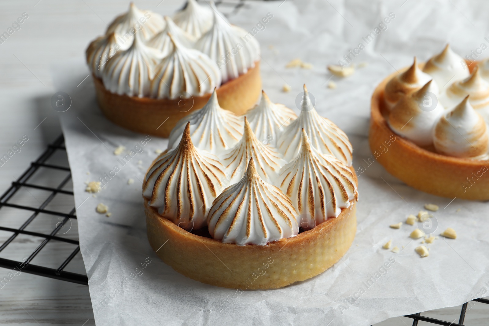 Photo of Tartlets with meringue on white table. Delicious dessert