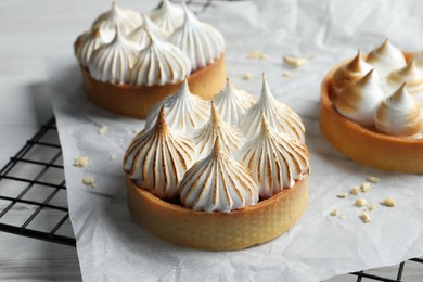 Photo of Tartlets with meringue on white table. Delicious dessert