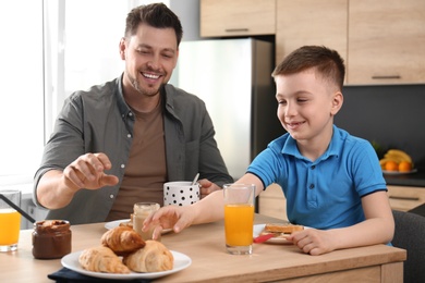 Dad and son having breakfast together in kitchen