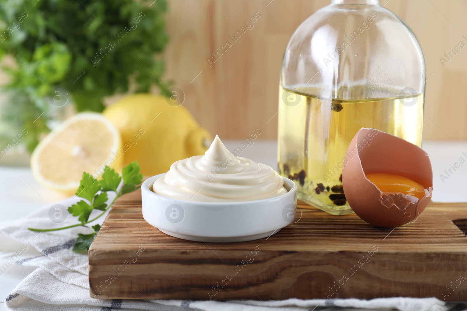 Photo of Fresh mayonnaise sauce in bowl and ingredients on table