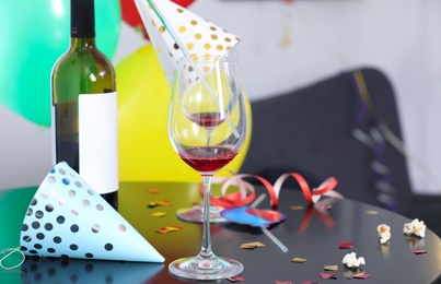 Messy table with bottle of wine and glasses against blurred background. After party chaos