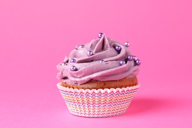 Photo of Delicious cupcake with bright cream and sprinkles on pink background