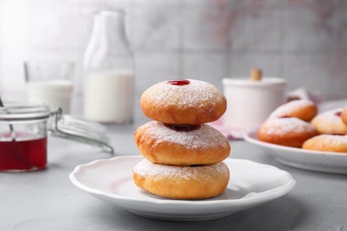 Photo of Hanukkah donuts with jelly and powdered sugar served on light grey table