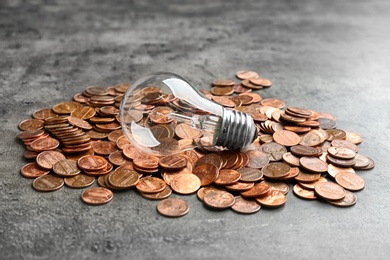 Pile of coins and light bulb on grey background