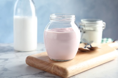 Glass jar of fresh yogurt on table