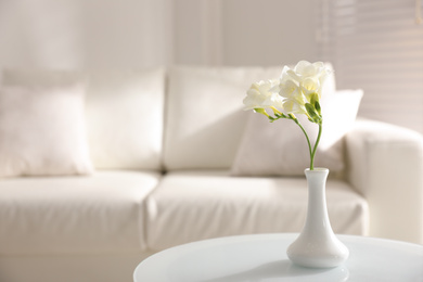 Photo of Beautiful white freesia flowers in light room, space for text