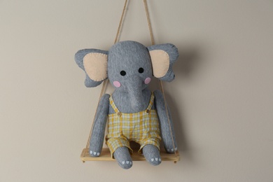 Photo of Shelf with cute toy elephant on beige wall. Child's room interior element