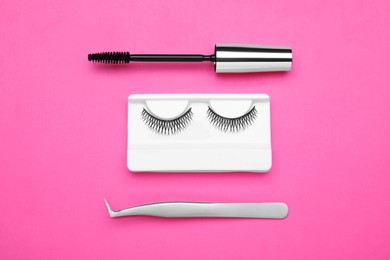 Fake eyelashes, mascara brush and tweezers on pink background, flat lay