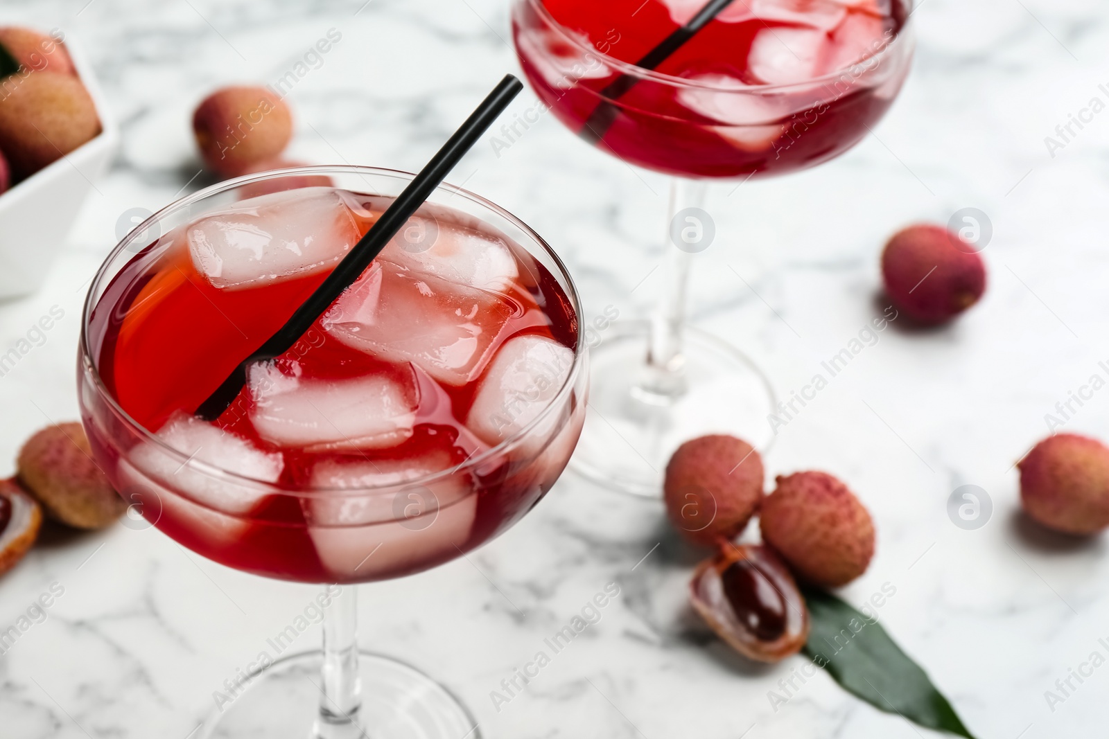Photo of Delicious lychee cocktail and fresh fruits on white marble table, closeup. Space for text