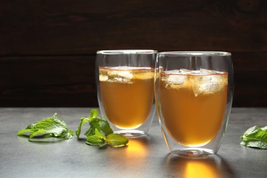 Photo of Glasses with aromatic mint tea and fresh leaves on table