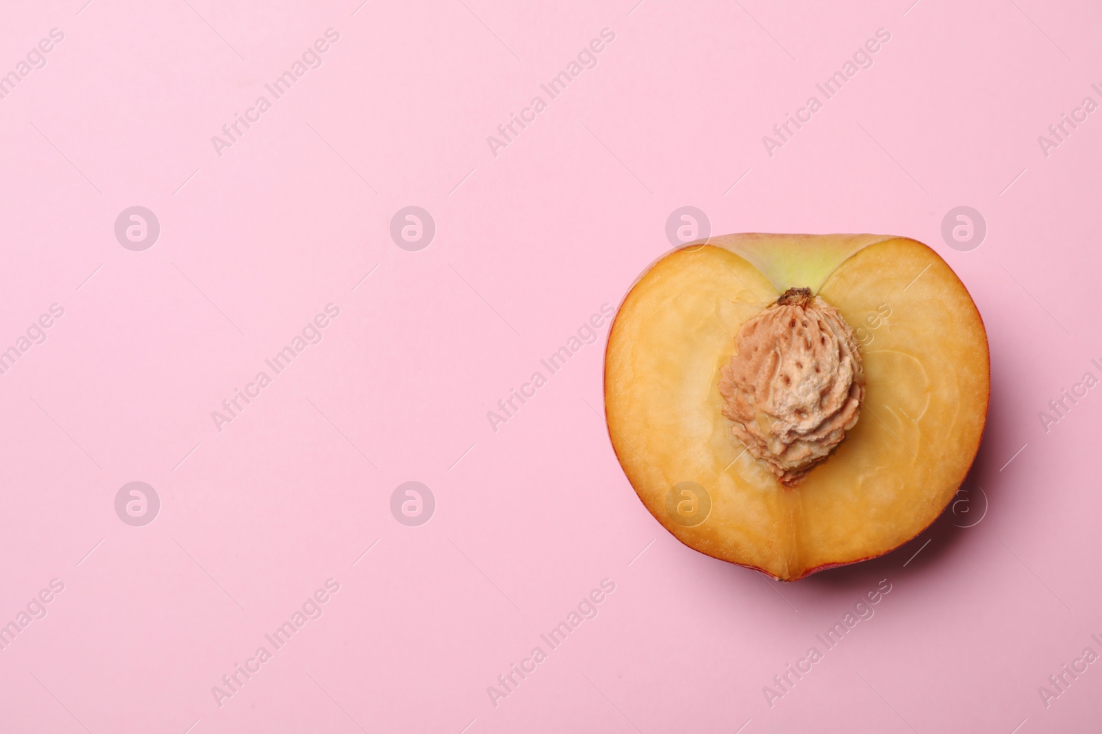 Photo of Half of sweet juicy peach on pink background, top view. Space for text