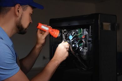 Photo of Repairman with flashlight fixing system unit indoors