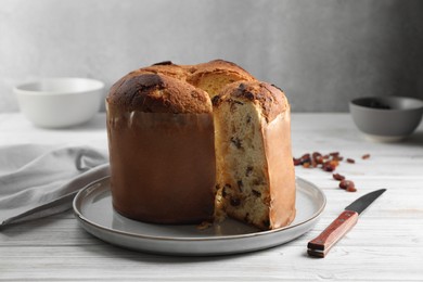 Delicious cut Panettone cake with raisins on white wooden table. Traditional Italian pastry