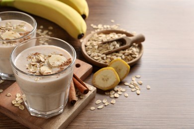 Photo of Tasty banana smoothie with oatmeal and cinnamon on wooden table, space for text