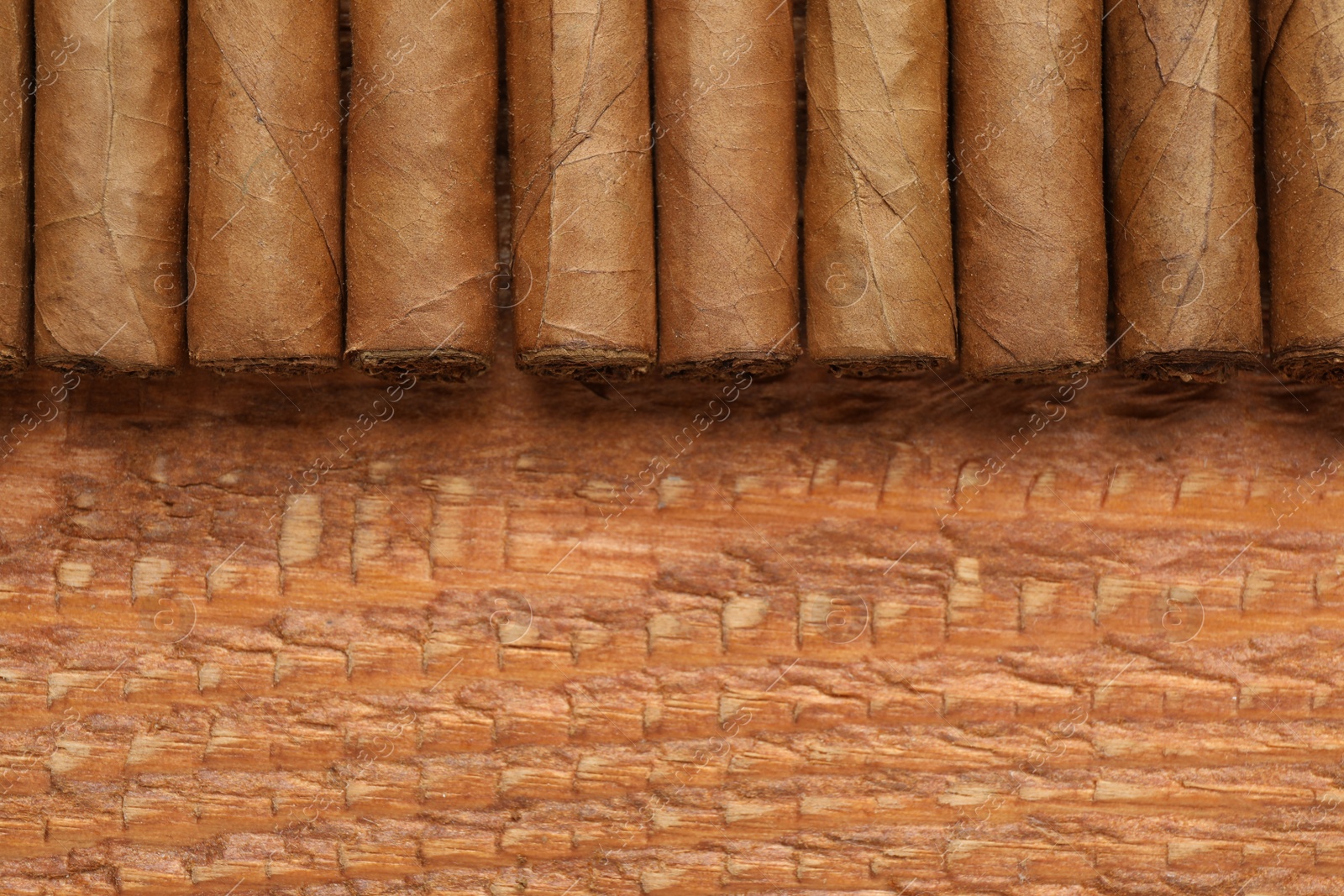 Photo of Many cigars on wooden table, flat lay. Space for text