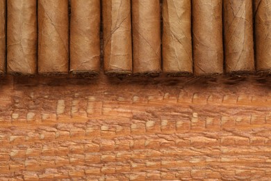 Photo of Many cigars on wooden table, flat lay. Space for text