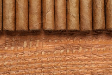 Many cigars on wooden table, flat lay. Space for text