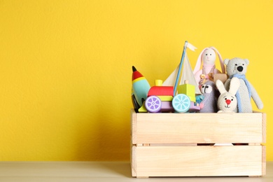 Photo of Crate with different toys on wooden table. Space for text