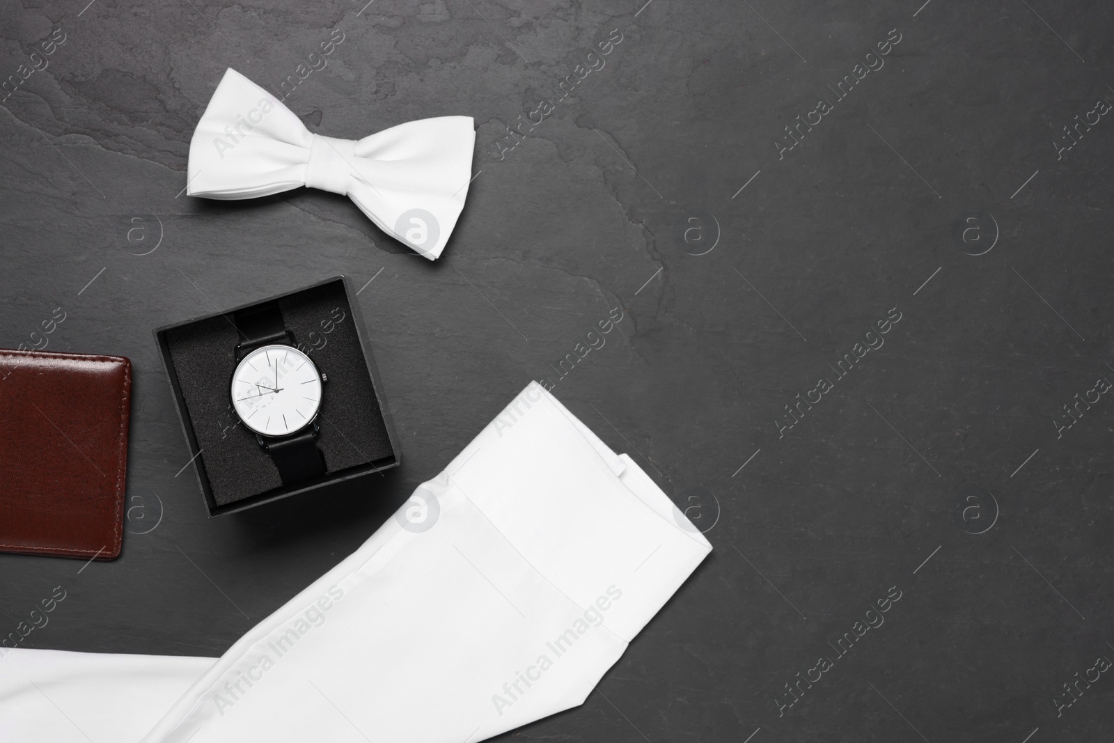 Photo of Stylish white bow tie, wristwatch, wallet and shirt on grey background, flat lay. Space for text