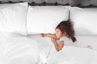 Photo of Cute little girl sleeping in bed, view from above. Space for text