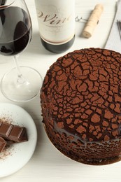 Photo of Delicious truffle cake, chocolate pieces and red wine on light wooden table