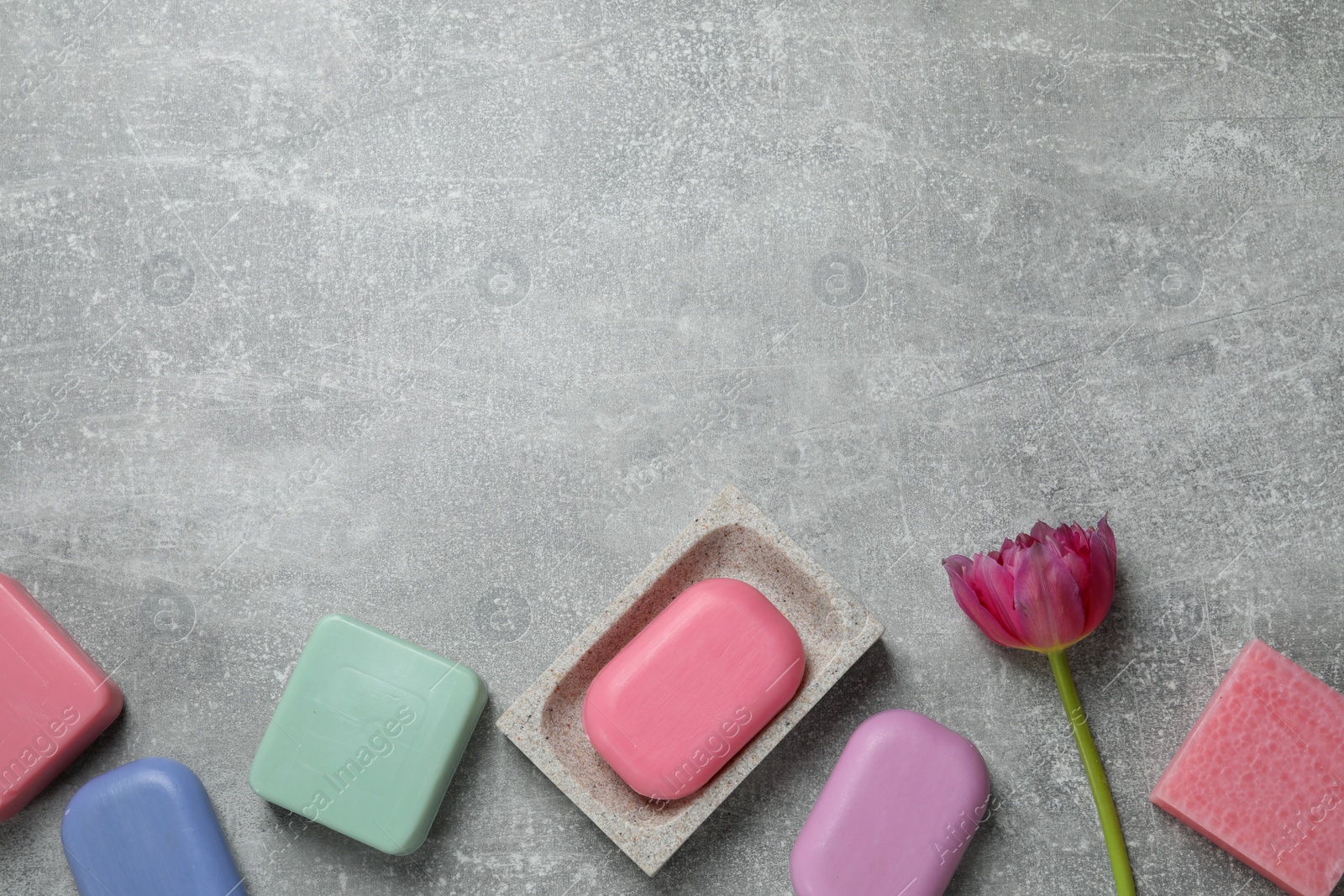 Photo of Many different soap bars and tulip on light grey table, flat lay. Space for text