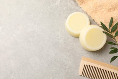 Photo of Solid shampoo bars, towel green twigs and comb on grey table, flat lay. Space for text