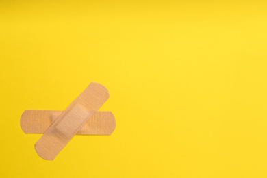 Photo of Sticking plasters on yellow background, top view. Space for text
