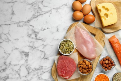 Photo of Different fresh products on white marble table, flat lay and space for text. Sources of essential amino acids