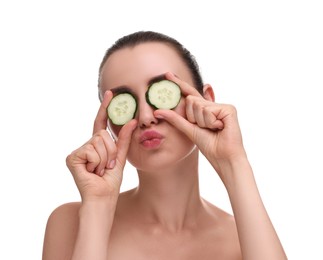Photo of Beautiful woman covering eyes with pieces of cucumber and blowing kiss on white background