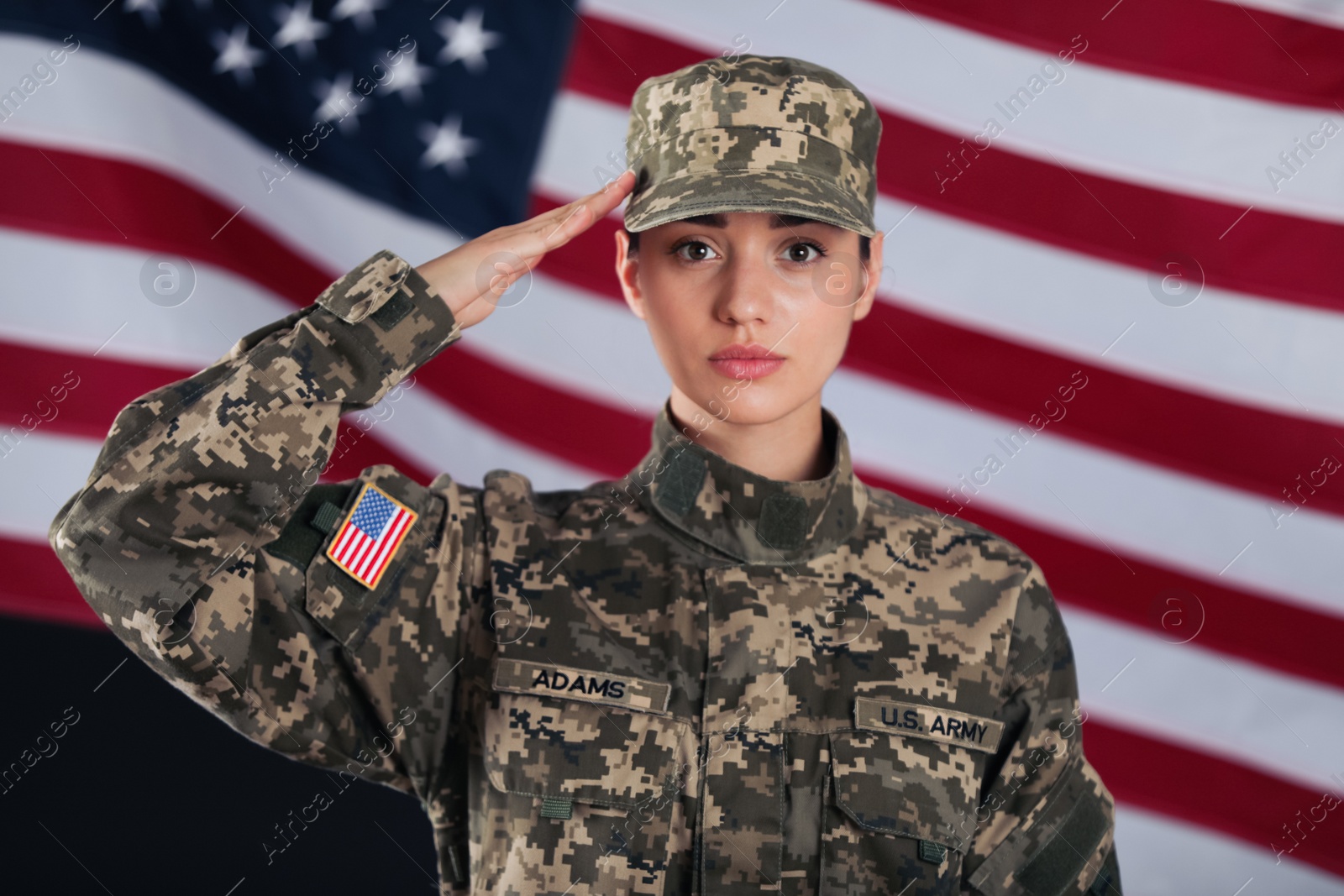 Photo of Female American soldier saluting with flag of USA on background. Military service