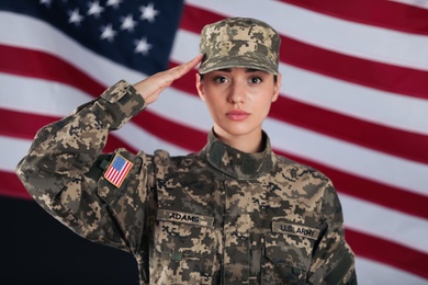 Female American soldier saluting with flag of USA on background. Military service