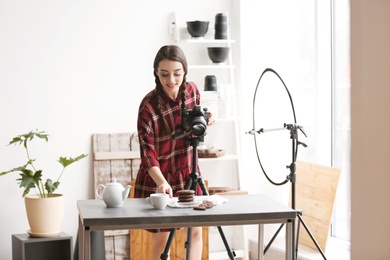 Photo of Young woman with professional camera preparing food composition in photo studio