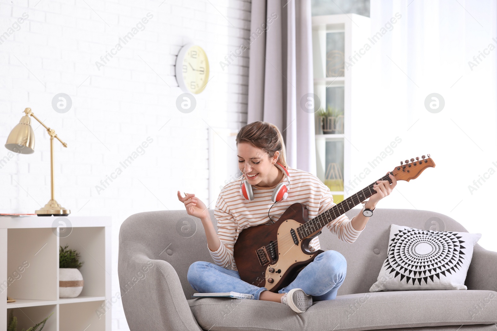Photo of Young woman with electric guitar composing song in living room
