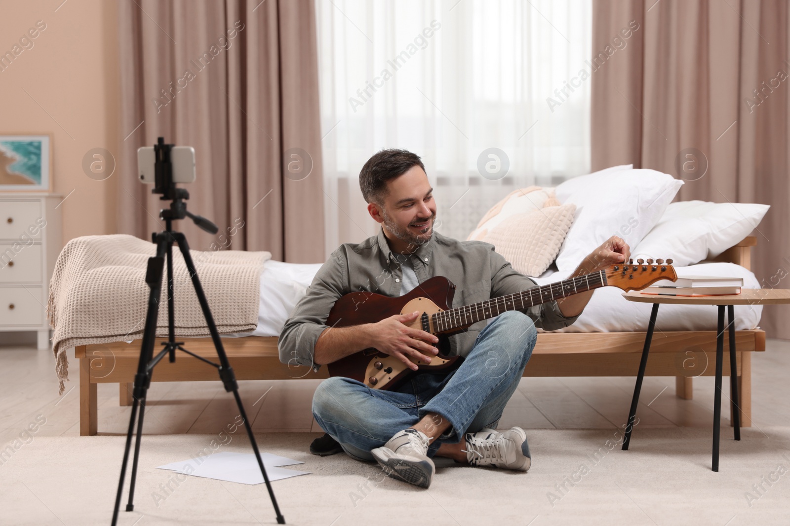 Photo of Music teacher tuning guitar while conducting online lesson at home. Time for hobby