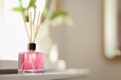 Aromatic reed air freshener on table against blurred background