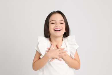 Portrait of cute little girl on light grey background