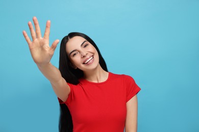 Photo of Happy woman giving high five on light blue background. Space for text