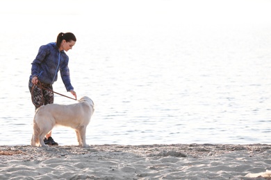 Young woman with her dog together on beach. Pet care