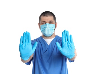 Photo of Doctor in protective mask showing stop gesture on white background. Prevent spreading of coronavirus