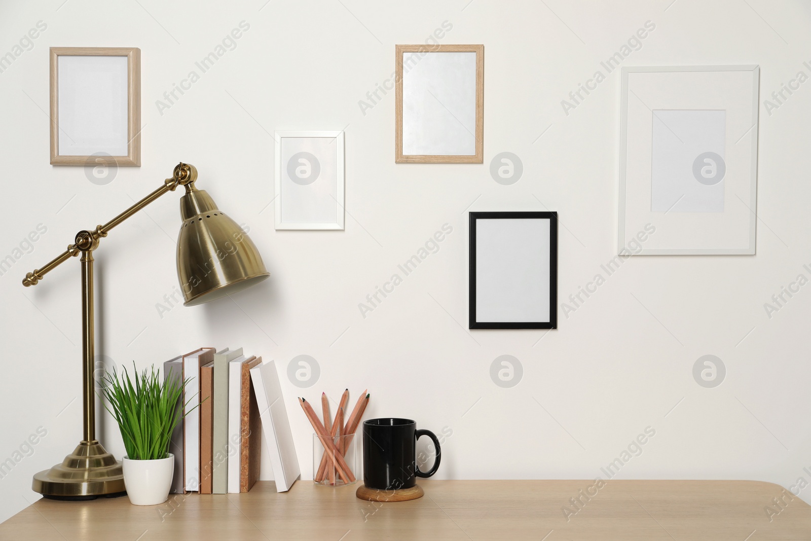 Photo of Comfortable workplace with wooden desk near white wall